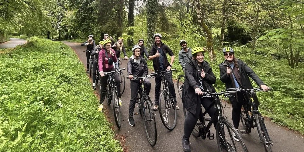 Group of people on bicycles wearing helmets on a forested path.
