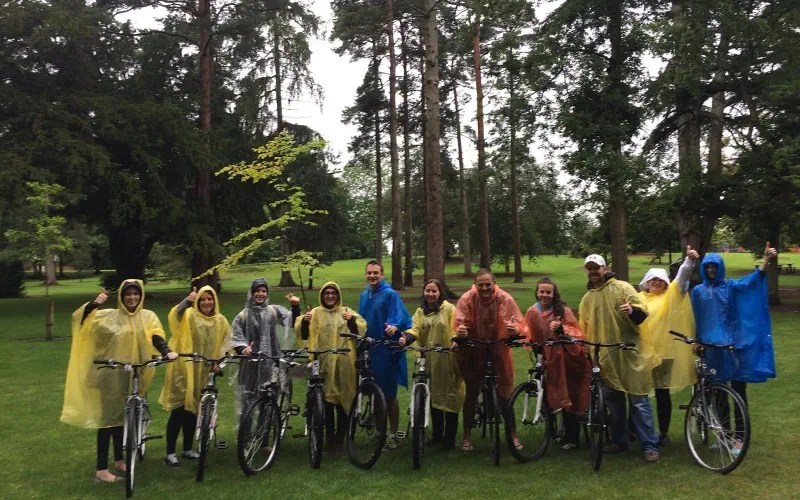 Group of people in raincoats with bikes in a park.